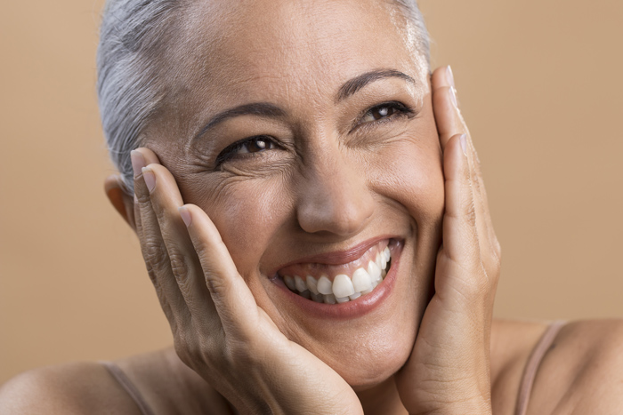 Mulher de meia idade sorrindo após alcançar efeito lifting facial.