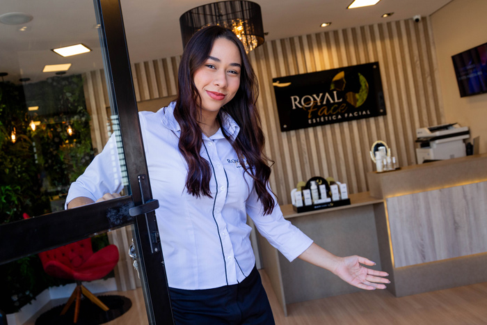 Entrada da clinica de estética Royal Face, com recepcionista abrindo a porta.