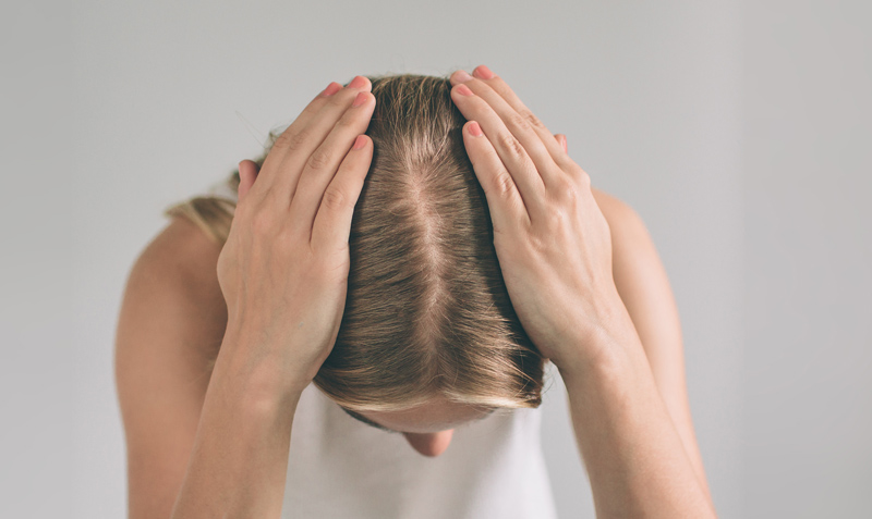 Mulher loira exibindo a raiz do cabelo, na parte superior da cabeça.