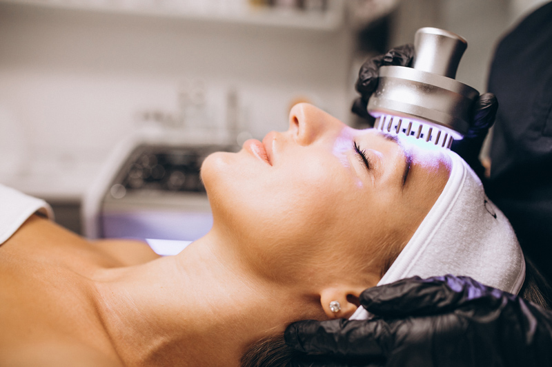 Mulher realizando LED terapia em clínica, um procedimento seguro e eficaz.