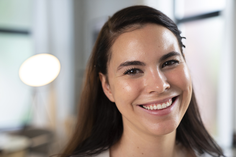 Rosto feminino sorridente, pele com viço, sedosa e saudável.