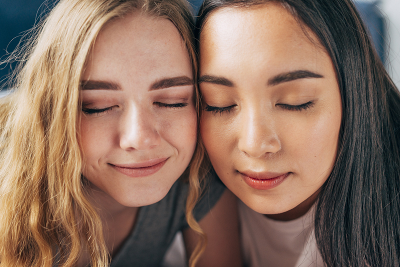 Duas mulheres com os olhos fechados, após realizar procedimentos estéticos zero downtime já podem ir para casa.