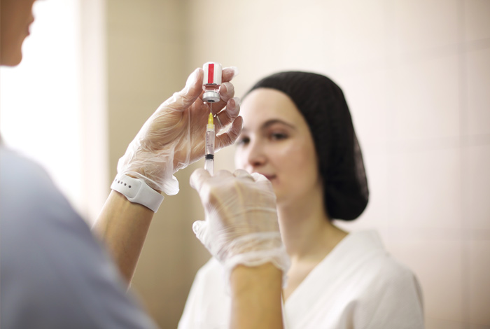 Profissional preparando seringa de aplicação de botox para aplicar em mulher.
