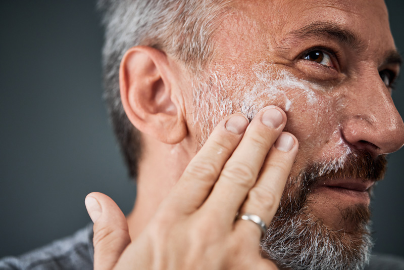 Homem realizando rotina de limpeza de pele, etapa de esfoliação.