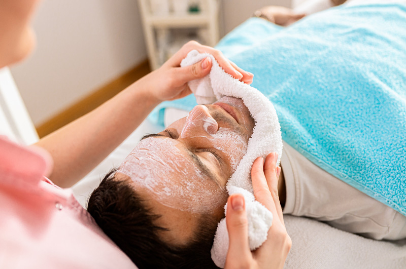 Limpeza de pele em homem, sendo realizada pro profissional de clínica estética.