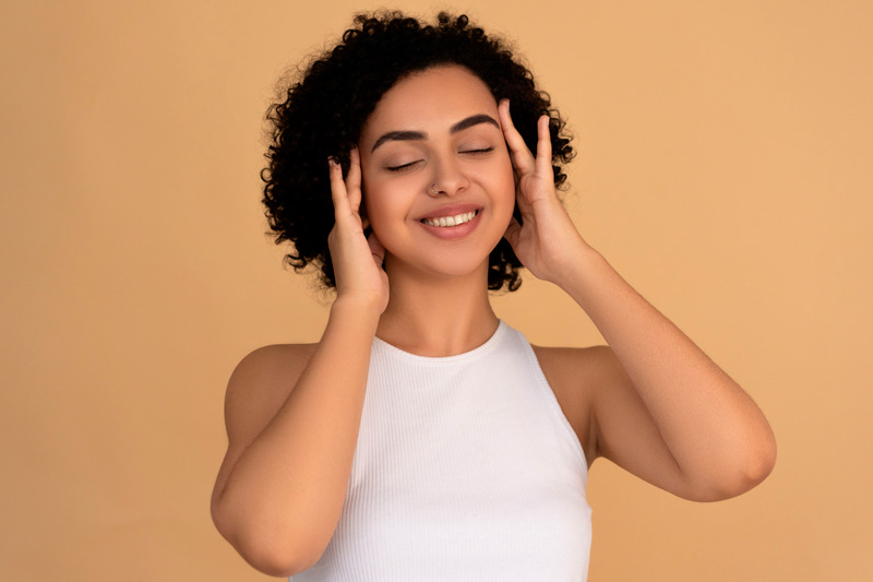 Mulher sorrindo com as mãos no rosto, ilustrando cuidados estéticos com produtos Allergan na Royal Face.