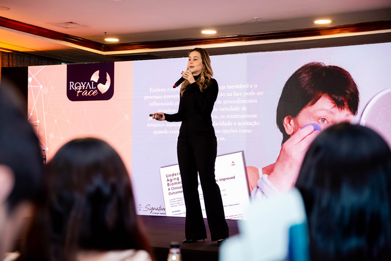 mulher com microfone no palco fazendo apresentação sobre franquia de estética