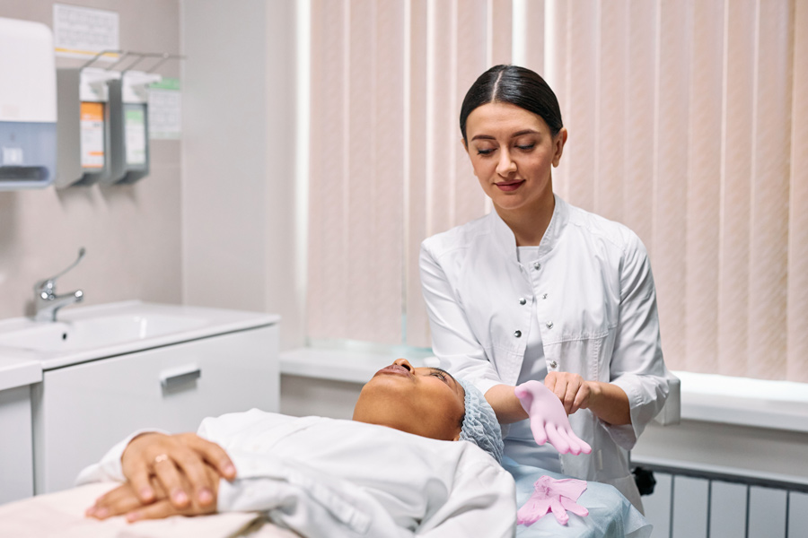 mulher deitada em maca em consultório de estética, conversando com a profissional sobre as melhores opções de tratamento para o seu caso específico.